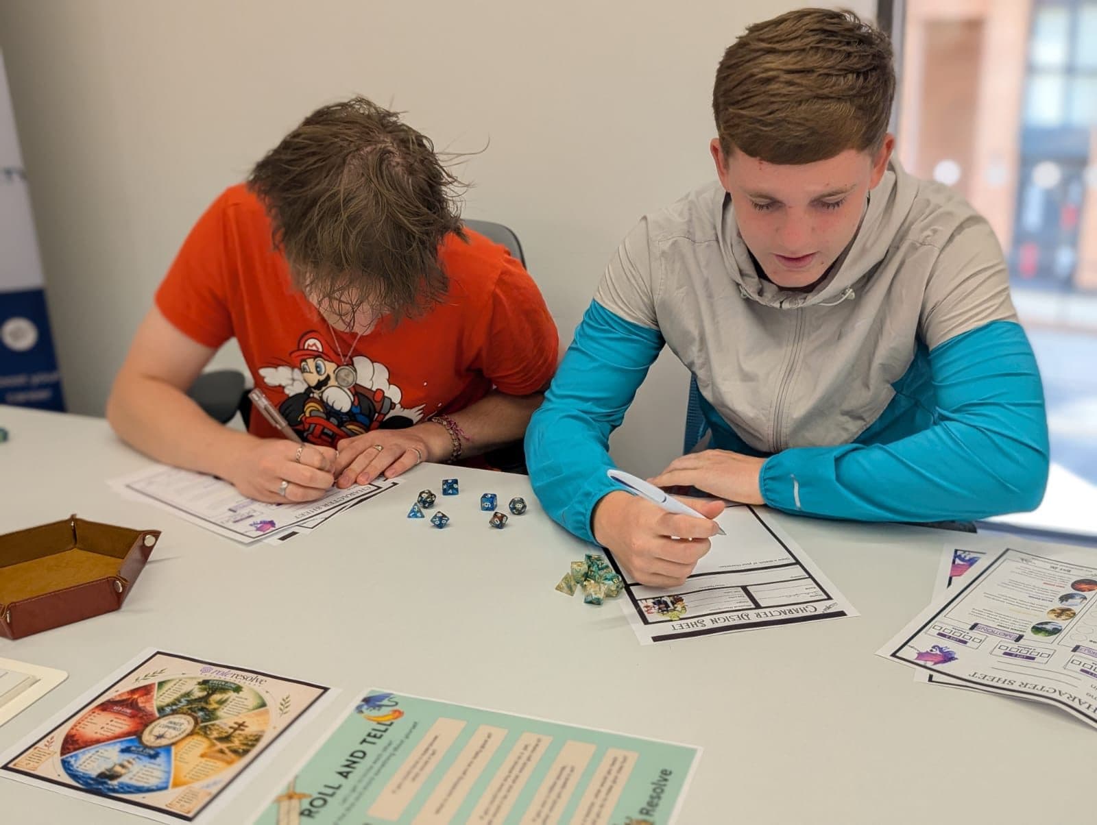 Two young people filling in character sheets during a Role Resolve storytelling session
